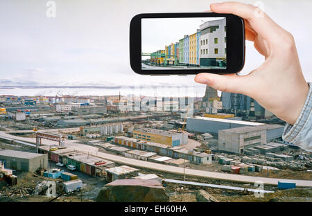 travel concept - tourist taking photo of Anadyr town skyline on mobile gadget in spring, Chukotka, Russia Stock Photo