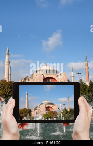 travel concept - tourist taking photo of Haghia Sophia through fountain on Sultanahmet square on mobile gadget, Istanbul, Turkey Stock Photo