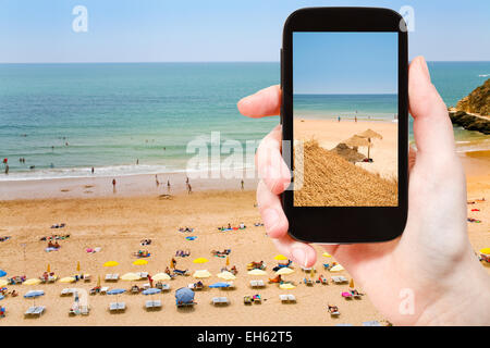 travel concept - tourist taking photo of Atlantic beach in Algarve, Portugal on mobile gadget Stock Photo