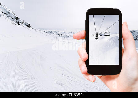 travel concept - tourist taking photo of skiing tracks and ski lift in Paradiski area, Alps, France on mobile gadget Stock Photo