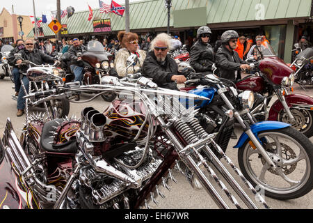 Leather clad bikers ride down Main Street past a customized Harley-Davidson chopper during the 74th Annual Daytona Bike Week March 7, 2015 in Daytona Beach, Florida. Stock Photo