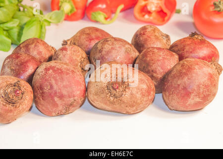 A pile of beetroots, in front of basil, pepper and tomato Stock Photo