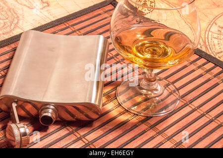Steel pocket flask and a glass with brown whiskey Stock Photo