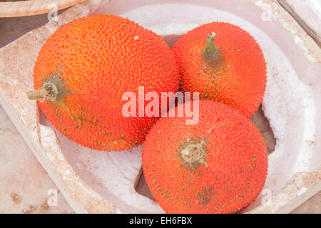 A few red gourd or gac fruits, at a market Stock Photo