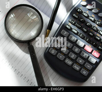 Image of selective focus shot of calculator magnifying glass and pen on notebook page Stock Photo