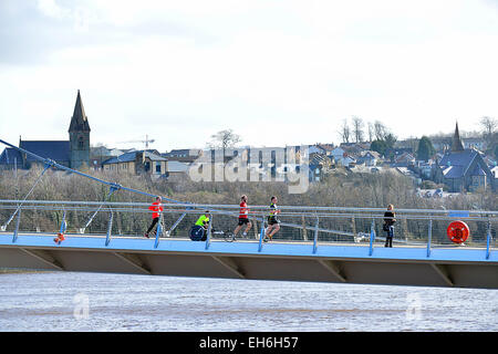 Londonderry, Northern Ireland, UK. 8th March, 2015. UK weather: Sunshine and showers in Londonderry, Northern Ireland - 08 March 2015. Competitors in the SSE Airtricity 10k half-marathon cross Londonderry's iconic Peace Bridge.  The forecast for Northern Ireland today is for sunny spells and scattered showers with brisk westerly winds. Credit:  George Sweeney/Alamy Live News Stock Photo