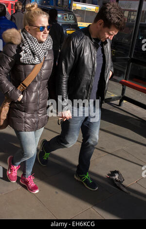 Pedestriands walk around a mangled, headless, pigeon lies on the pavement on London's Piccadily. Stock Photo