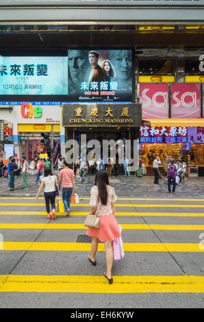 People walking over the crosswalk in front of the infamous Chungking Mansions, Nathan Road, Tsim Sha Tsui, Kowloon, Hong Kong Stock Photo