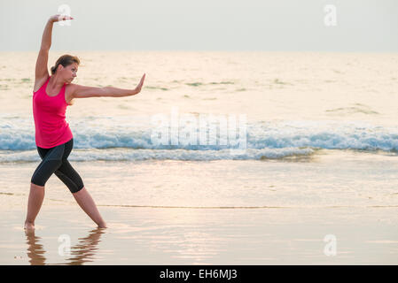 Concentrated woman doing yoga on the beach Stock Photo