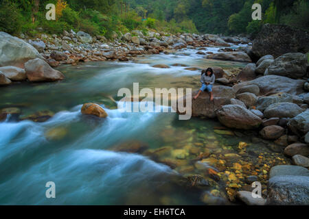 A lady reading book near the bank of Tirthan River (Himachal Pradesh) Stock Photo