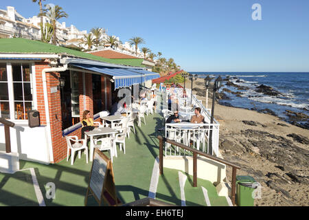 Tourists in winter season at beach bar, cafe, restaurant at coast Southern Spain, La Cala, Andalusia. Spain. Stock Photo