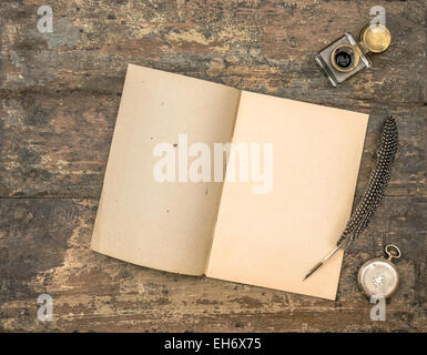 Open diary book and vintage office supplies on wooden table. Feather pen and inkwell on textured background Stock Photo