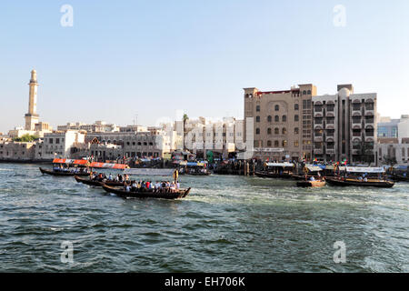View over Dubai Creek from Deira to Bur Dubai. Abras, typical ferry boats in Dubai, are crossing the river; the minaret of the G Stock Photo