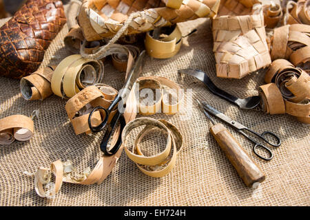 Closeup view of tools, instruments and work in progress of bast shoes craftsman. Scissors, ready made bast shoes, bast and lime Stock Photo