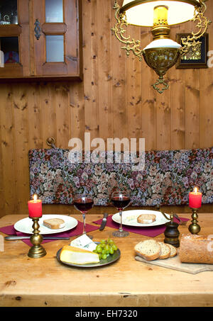 Intimate dinner table setting with candles and wine served in a romantic mountain chalet in the Alps. Stock Photo