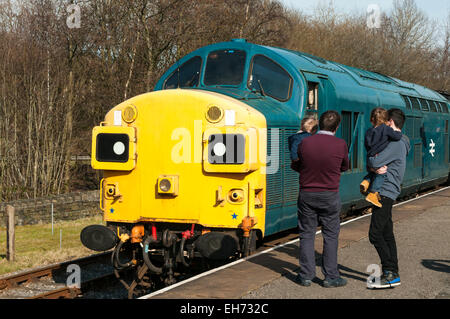 Two Dads carrying their toddlers looking at a 1980s class 37 diesel loco at Rawtenstall on the East Lancs Railway Stock Photo