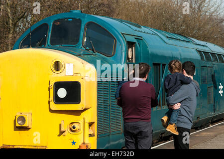 Two Dads carrying their toddlers looking at a 1980s class 37 diesel loco at Rawtenstall on the East Lancs Railway Stock Photo