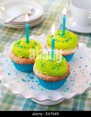 Birthday cupcakes. Angel food cupcakes with vanilla frosting, sprinkles, and lit candles. Stock Photo