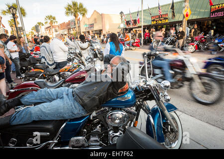 Daytona Beach, FL, USA. 8th Mar, 2015. A biker rests on his Harley-Davidson as others ride past along Main Street during the 74th Annual Daytona Bike Week March 8, 2015 in Daytona Beach, Florida. More than 500,000 bikers and spectators gather for the week long event, the largest motorcycle rally in America. Credit:  Richard Ellis/ZUMA Wire/Alamy Live News Stock Photo