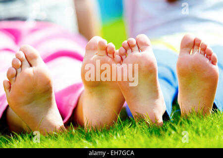 Children sitting side by side with bare feet dangling Stock Photo - Alamy