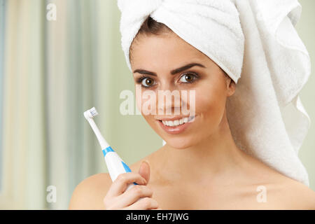 Woman Brushing Teeth With Electric Toothbrush In Bathroom Stock Photo