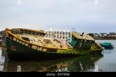 The rotten hulk of an abandoned fishing boat sinking into the mudflaps at Hooe Lake in Plymouth Stock Photo