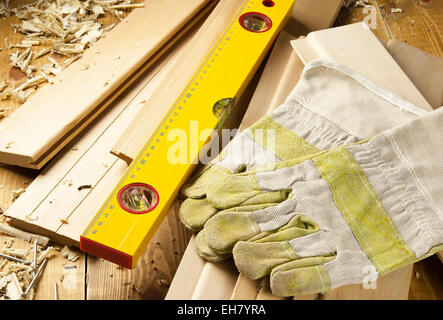 Carpenters level, nails and work gloves are on a wooden planks Stock Photo