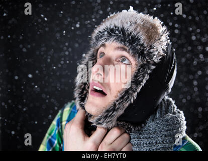 Surprised young man looking up with snow on background Stock Photo