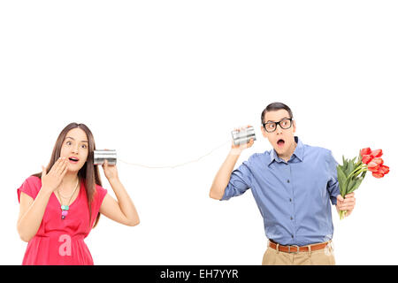 Man and a woman talking through a tin can phone isolated on white background Stock Photo