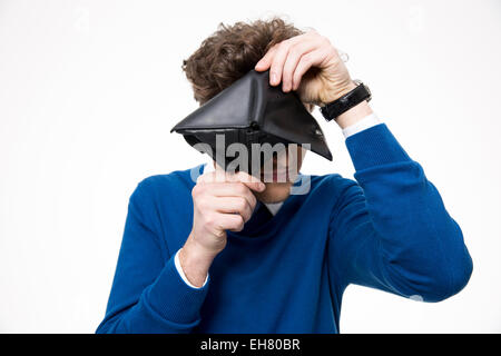 Young man looking through empty wallet at the camera Stock Photo