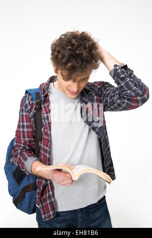 Portrait of a young male student reading book over gray background Stock Photo