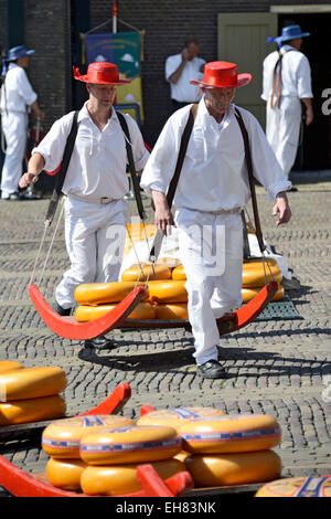 Cheese porters carrying cheese wheels on wooden sledges at the Friday Cheese Market, Waagplein Square, Alkmaar, Netherlands Stock Photo
