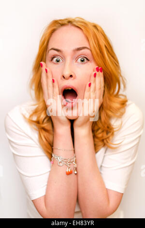 Close up portrait of a young caucusian woman with curly ginger hair scared afraid and anxious. Screaming with eyes wide open. Hu Stock Photo