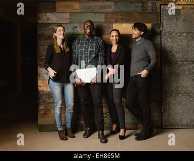 Portrait of young professionals laughing while standing together in office. Multi ethnic business team looking happy together.