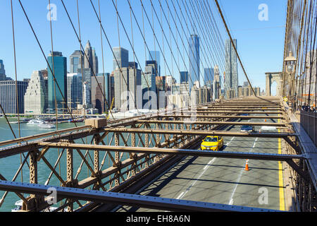 Yellow taxi cab crossing Brooklyn Bridge with the Lower Manhattan skyline behind, New York City, New York, USA Stock Photo