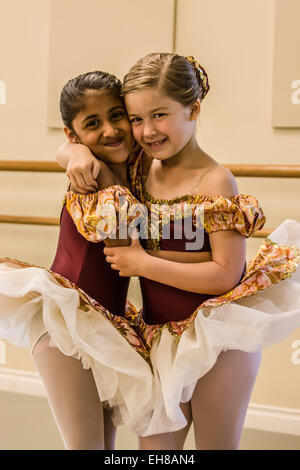 Seven year old girls hugging, showing their friendship, at a ballet dance dress rehearsal in a studio Stock Photo