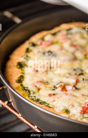 Vegetarian, pesto, multi-grain, thick-crust pizza baking in the oven Stock Photo