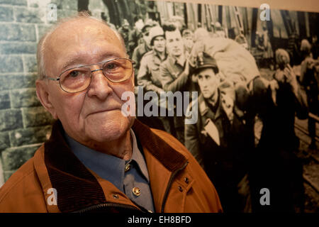 German World War II veteran Herbert Groschopp stand next to a photograph published by US magazine 'Stars and Stripes' which shows him (pn the photo, L, front) crossing the Remagen Bridge as a prisoner of war after the Battle of Remagen on 7 March 1945, during a memorial ceremony in Remagen, Germany, 7 March 2015. The memorial ceremony commemorated the capture of the railway bridge by Allied troops on 7 March 2015. US troops were surprised when the found one of the last remaining bridges crossing the river Rhine intact at Remagen and sallied out to capture the bridge. The capture marks the fir Stock Photo