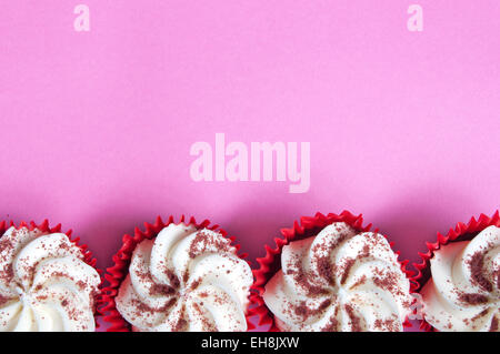 Cream cupcakes over a pink backdrop Stock Photo