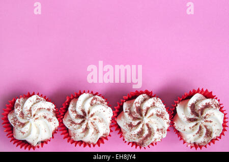 Cream cupcakes over a pink backdrop Stock Photo