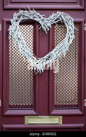 Close-up of a front door to a house with a heart-shaped wreath decoration Stock Photo