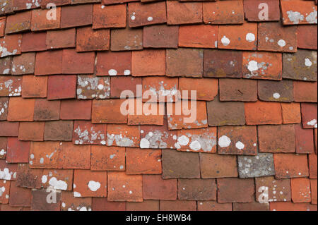 Overlapping mixed  handmade clay tiles roofing tile hanging on the surface of an oast house a cheap way of keeping out the rain Stock Photo