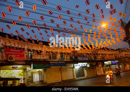 Motorists riding at night below decorative flags on Tanao street in Khaosan Road area, Bangkok, Thailand. Stock Photo