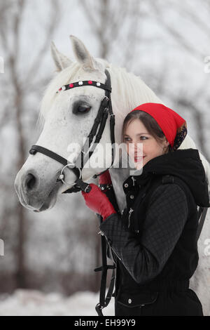 Horse and pretty brunette woman in winter countryside Stock Photo