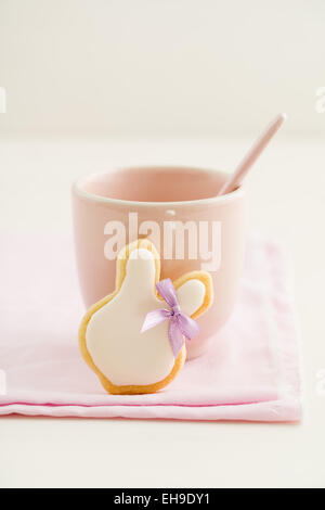 Easter bunny sugar cookie with hair ribbon and a pink cup Stock Photo