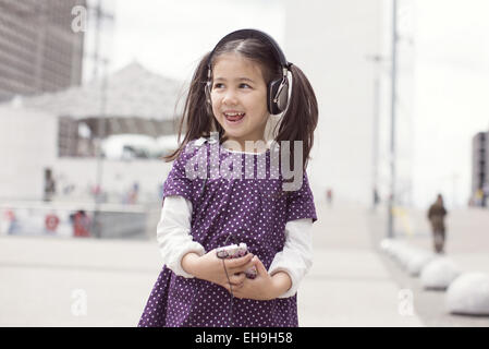 Girl listening to headphones and singing outdoors Stock Photo