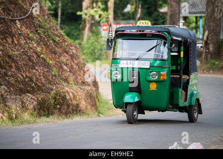 Tuk tuk motor taxi driving along main road through tea plantations in the Sri Lanka highlands, around Adams Peak,  Asia Stock Photo