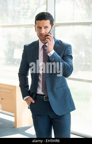 Executive talking on cell phone in office Stock Photo