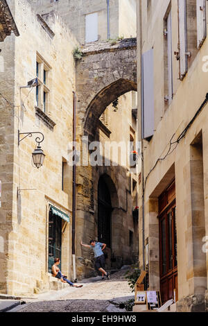 Young couple talking under archway in narrow street in Saint-Emilion, Gironde, Aquitaine, France Stock Photo