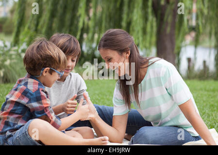 Mother teaching her sons how to thumb wrestle Stock Photo